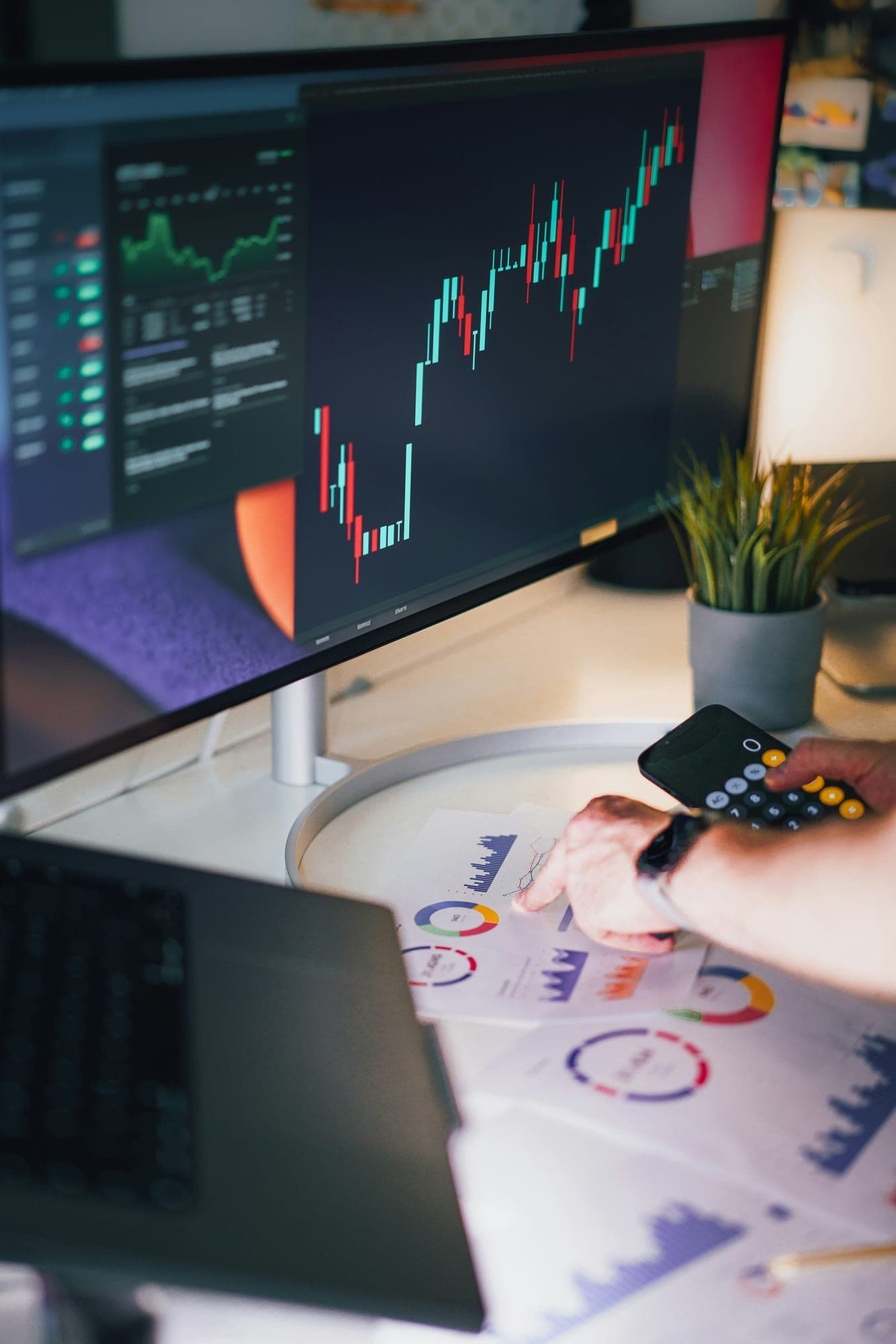 An analyst reviewing market charts on a monitor and a tablet